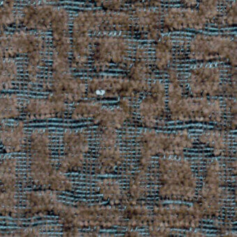 Textured fabric swatch with repeating brown and tan irregular shapes on a dark blue grid, showing a woven, nubby pile texture.