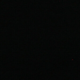 Minimalist composition of a black background with a single red dot in the lower right, creating a stark, isolated visual element.