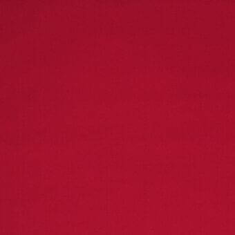 Red geometric fabric with a matte finish, tight weave, and subtle stretch texture, presented in a studio setting.
