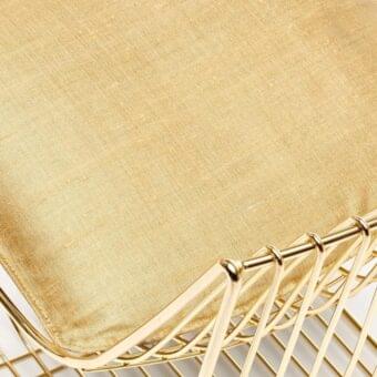 Chair seat upholstered in gold Delhi Oro R820 111 fabric with woven texture, supported by geometric gold metal frame.