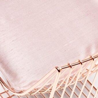 Chair seat cushion upholstered in dusty rose textured fabric, with rose gold metal frame featuring a geometric grid pattern.
