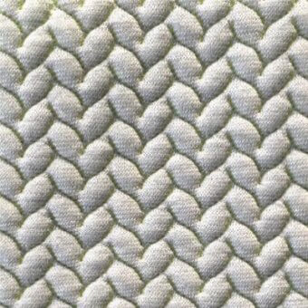 Chevron fabric texture, light gray and iridescent green, features a quilted, repeating zigzag pattern with rounded geometric shapes.