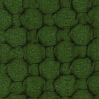 Green textured fabric with repeating raised hexagon pattern, matte finish, visible stitching, identified as Moroso Big Pois Grass textile.