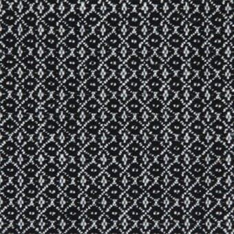 Black and white textile sample with dense, repeating floral-geometric motifs in a tight jacquard weave, creating a textured, interwoven pattern.