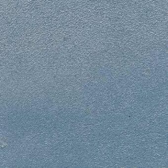Blue fabric texture with granular weave, matte finish, and tonal variations; slight surface irregularities and a dark speck are visible.