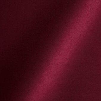 Cardinal pink satin fabric texture displaying vertical folds, labeled “reflex fabric amsterdam 53 cardinal pink” for upholstery or drapery.