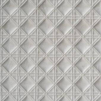 Quilted fabric texture in light gray features a diamond grid pattern with precise stitching, showcasing a subtle matte finish and refined detail.