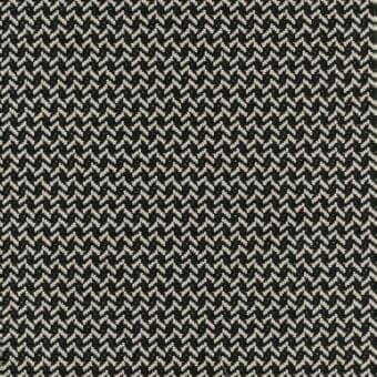 Herringbone textile with black and beige woven pattern, displaying angled lines and a dense, uniform texture in a studio setting.