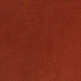 Reddish-brown textured rug with a dense, granular weave and uniform color, presented against a neutral, blurred background.