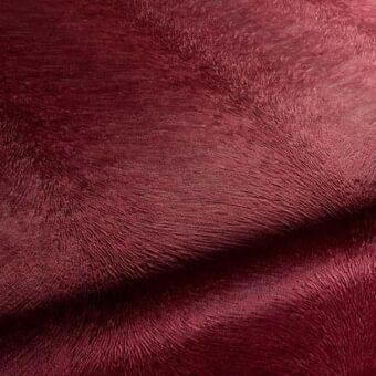 Burgundy rug sample with a linear woven texture, displaying rich saturated color and soft folds, against a neutral backdrop.