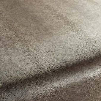 Rug, woven texture, taupe and gray color palette, featuring undulating linear ridges creating a wave-like pattern on a light gray background.