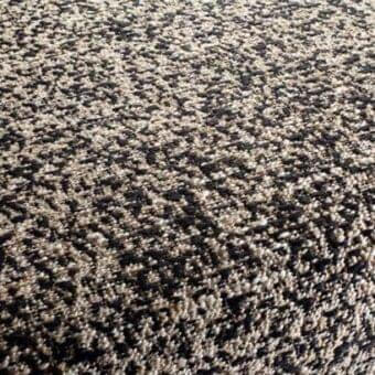 Beige and brown speckled rug with a dense looped pile texture, featuring warm earthy tones and a granular visual effect.