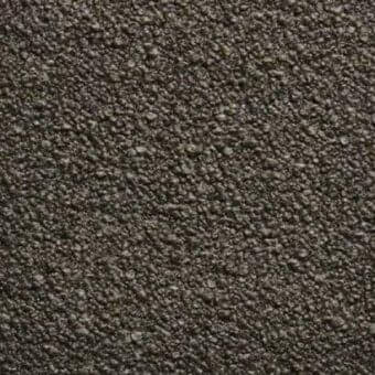 Dark gray textured rug with granular surface composed of irregular particles, displaying subtle tonal variations under diffused studio lighting.