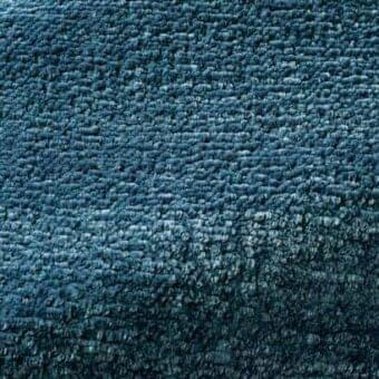 Teal Rugiano Tempesta rug with dense looped pile, gradient color from turquoise to deep teal, matte finish, and textured, uneven surface.