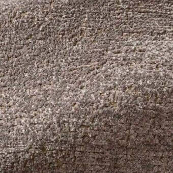 Rugiano ciottolo rug, gray-brown textured fabric, rounded pebble-like surface with granular, uneven composition and studio lighting.