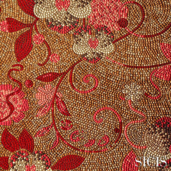 Sicis Dolium fabric mosaic, red and gold floral tessellation, intricate tilework with swirling vines, warm brown background, SICIS branding.