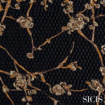 Sicis Flores Gold fabric with metallic gold floral motifs on a dark textured black background, detailed blossoms and repeating square pattern.