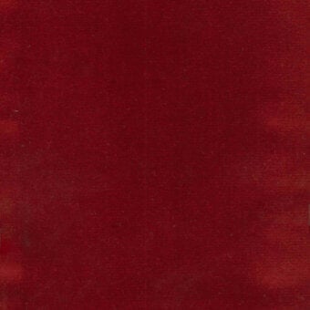 Deep red velvet fabric with a textured surface and directional fibers, displaying a saturated crimson color and uniform pile, with a small label.