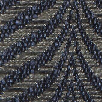 Verzelloni fabric texture, dark indigo ribbed weave, densely knotted surface with heathered tonal variations and consistent diagonal pattern.