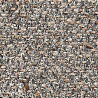 Gray and tan tweed fabric texture with a dense, irregular weave and short fibers, displaying a mottled surface with circular yarn variations.