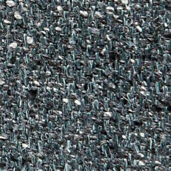 Dark teal woven fabric texture with gray and off-white flecks, displaying a tight, irregular pile and subtle manufacturing markings.