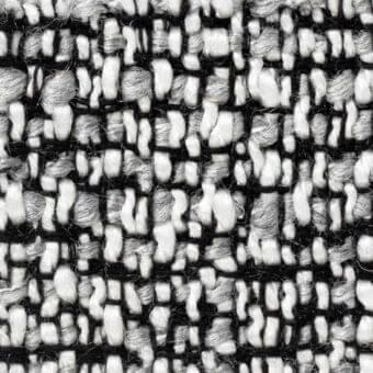 Woven tweed fabric with black, white, and gray vertical lines and irregular yarn blocks, displaying a nubby texture and visible grid weave.