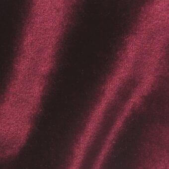 Red-burgundy velour fabric sample, Vismara Brilliant Velour VE17, displays a dense short pile and directional sheen with subtle color variations.