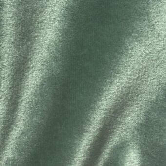 Green velour fabric texture with a plush, dense pile and subtle sheen, displaying linear shadows and the text “vismara brilliant velour ve23”.
