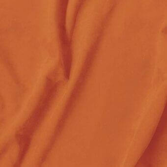Orange draped fabric with a smooth, lustrous texture and soft folds, exhibiting a gentle sheen and undulating waves in diffused light.