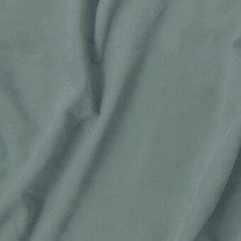 Dusty teal fabric swatch with matte finish, draped in soft folds revealing a smooth, velvety texture; Vismara eco nabuk textile sample.