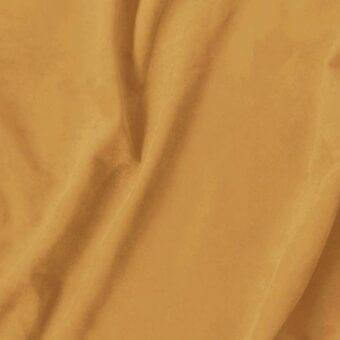 Golden-brown draped fabric with a smooth, lustrous texture and flowing folds, exhibiting a soft sheen and uniform background.