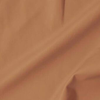 Terracotta leather swatch with soft, matte texture; smooth folds display tonal variations, natural grain, and a velvety appearance; studio lighting.